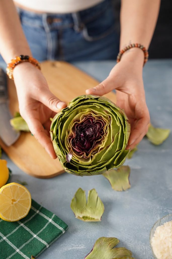 fresh-artichoke-held-over-cutting-board-31979190