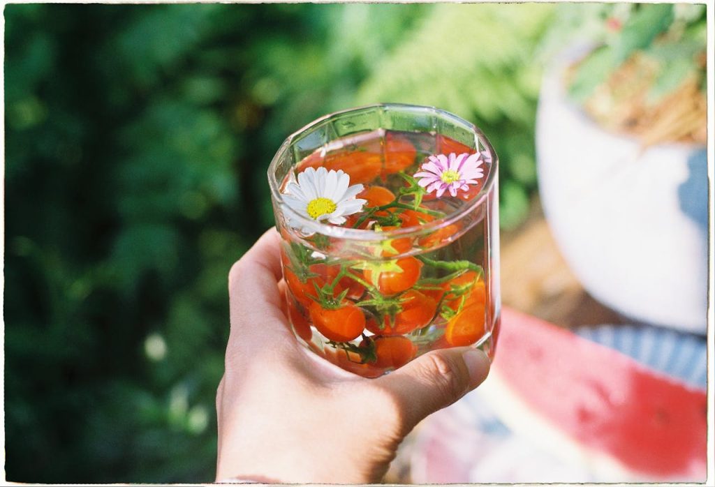 hand-holding-glass-with-edible-flowers-and-cherry-tomatoes-31985976