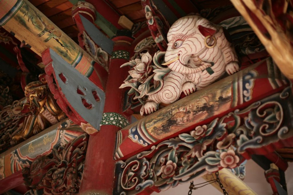 Capture of a detailed elephant carving in a traditional temple ceiling, highlighting vibrant colors and craftsmanship.